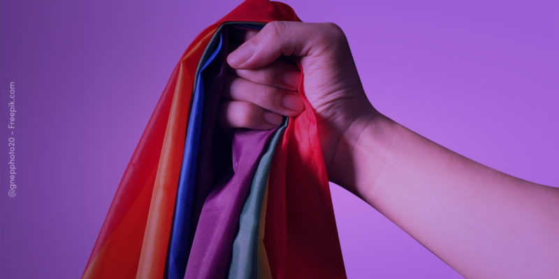 mão segurando bandeira LGBTQIA+